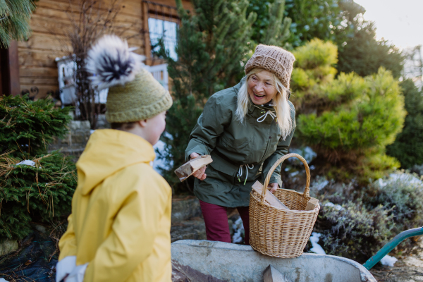 A boy with Down syndrome working in garden in winter with his grandmother.