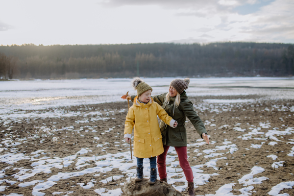 A happy little boy with Down syndrome with his grandmother outside by lake in winter.