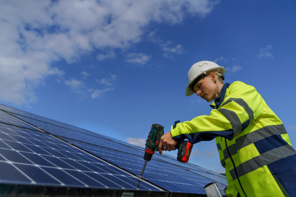 A woman engineer installing solar photovoltaic panels on roof, alternative energy concept.