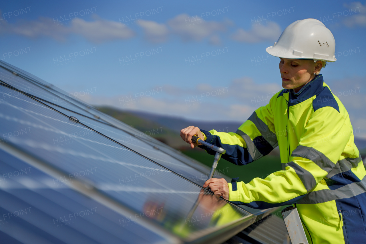 A woman engineer installing solar photovoltaic panels on roof, alternative energy concept.