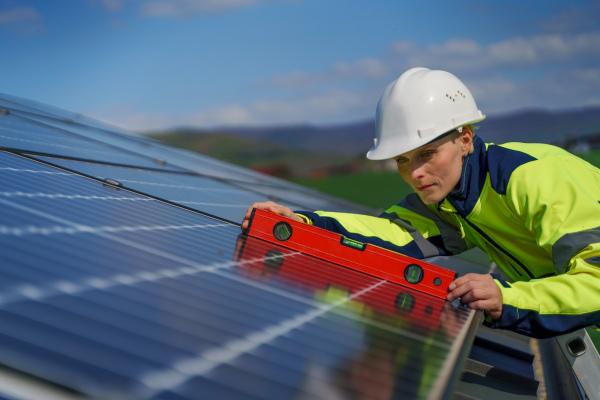 A woman engineer installing a solar photovoltaic panels on roof, alternative energy concept.