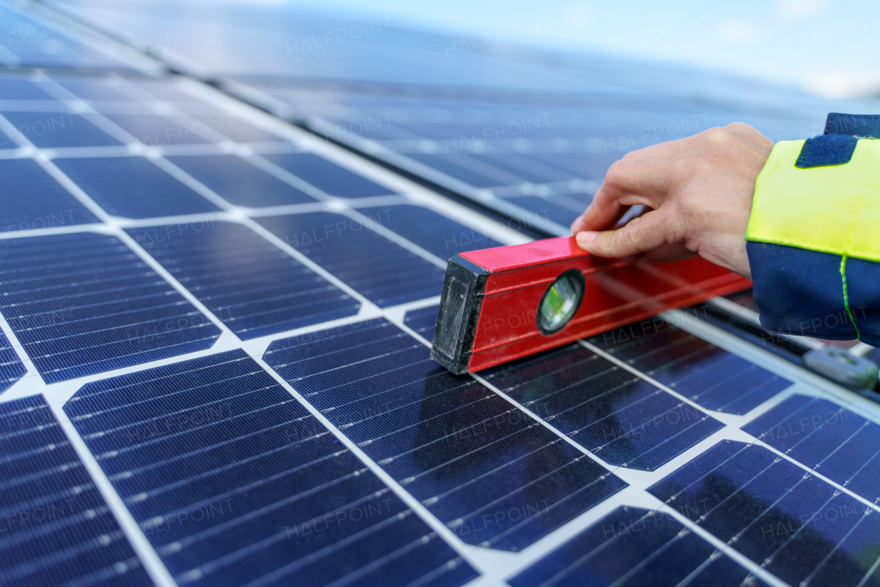 A close-up of woman engineer measuring solar photovoltaic panels on roof, alternative energy concept.