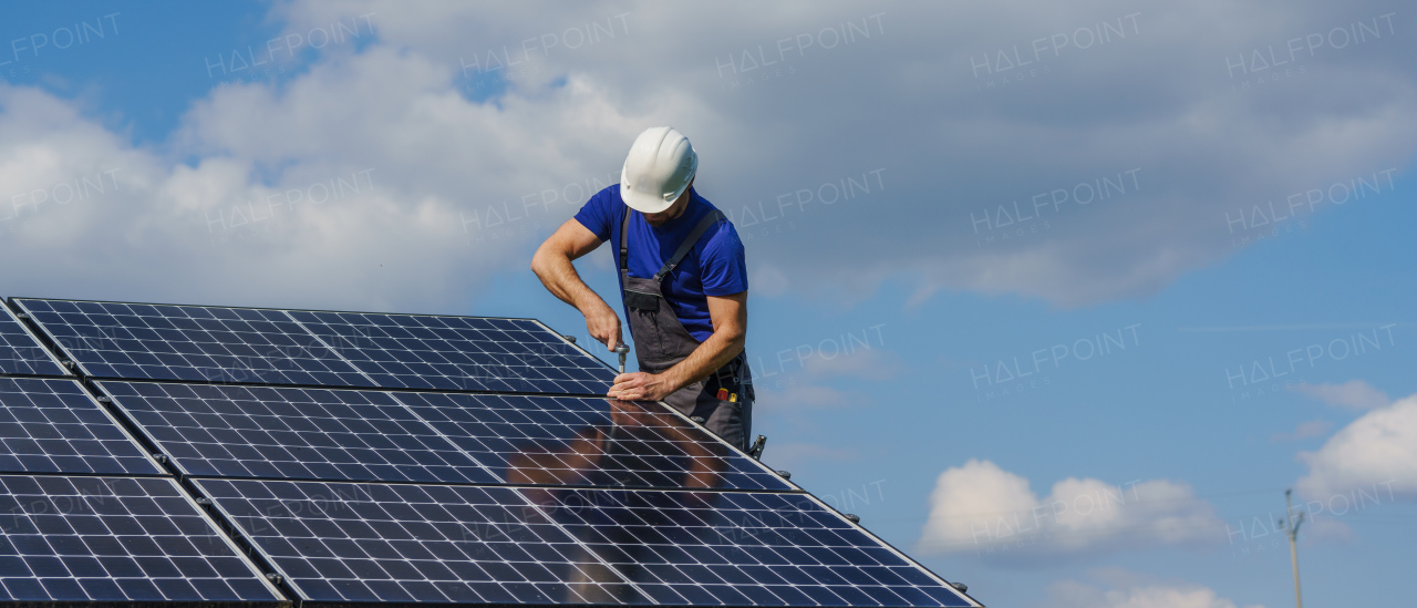 A man worker installing solar photovoltaic panels on roof, alternative energy concept.