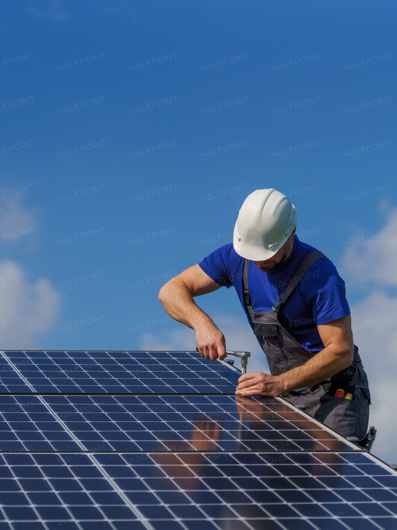 A man worker installing solar photovoltaic panels on roof, alternative energy concept.