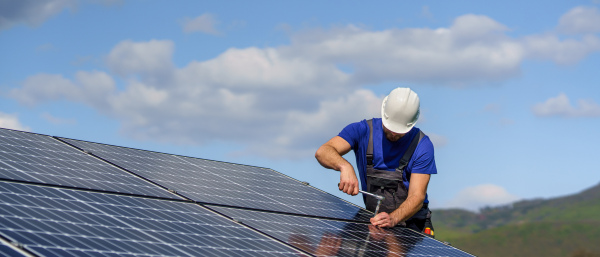 A man worker installing solar photovoltaic panels on roof, alternative energy concept.