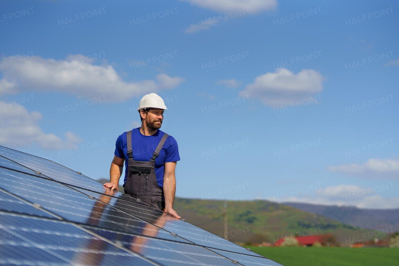 A man worker installing solar photovoltaic panels on roof, alternative energy concept.