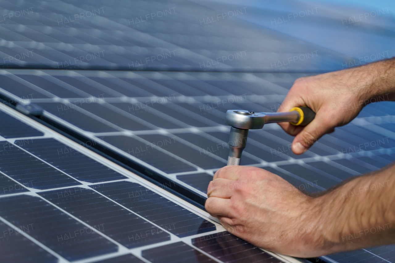 A man worker installing solar photovoltaic panels on roof, alternative energy concept.