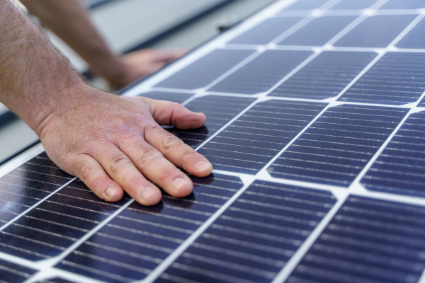 A man worker installing solar photovoltaic panels on roof, alternative energy concept.