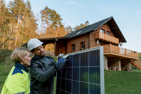 A smiling handyman solar installer carrying solar module while installing solar panel system on house.