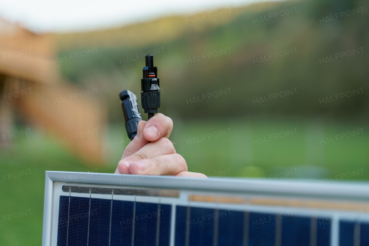 A close-up of solar installer carrying solar module while installing solar panel system on house.