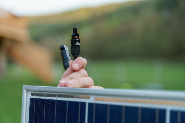 A close-up of solar installer carrying solar module while installing solar panel system on house.