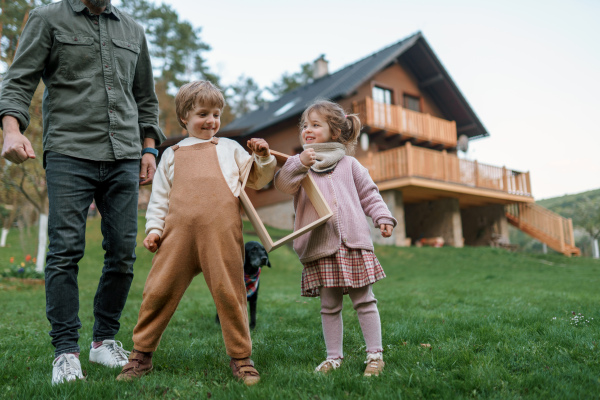 A happy family is standing near their modern house, smiling and looking at camera