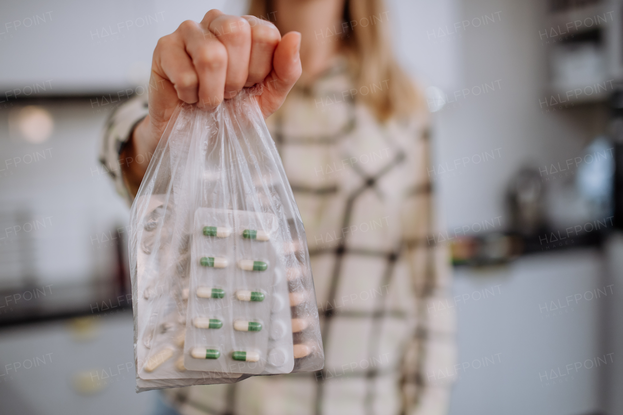 A woman's hand holding expired pills ready to recycle.