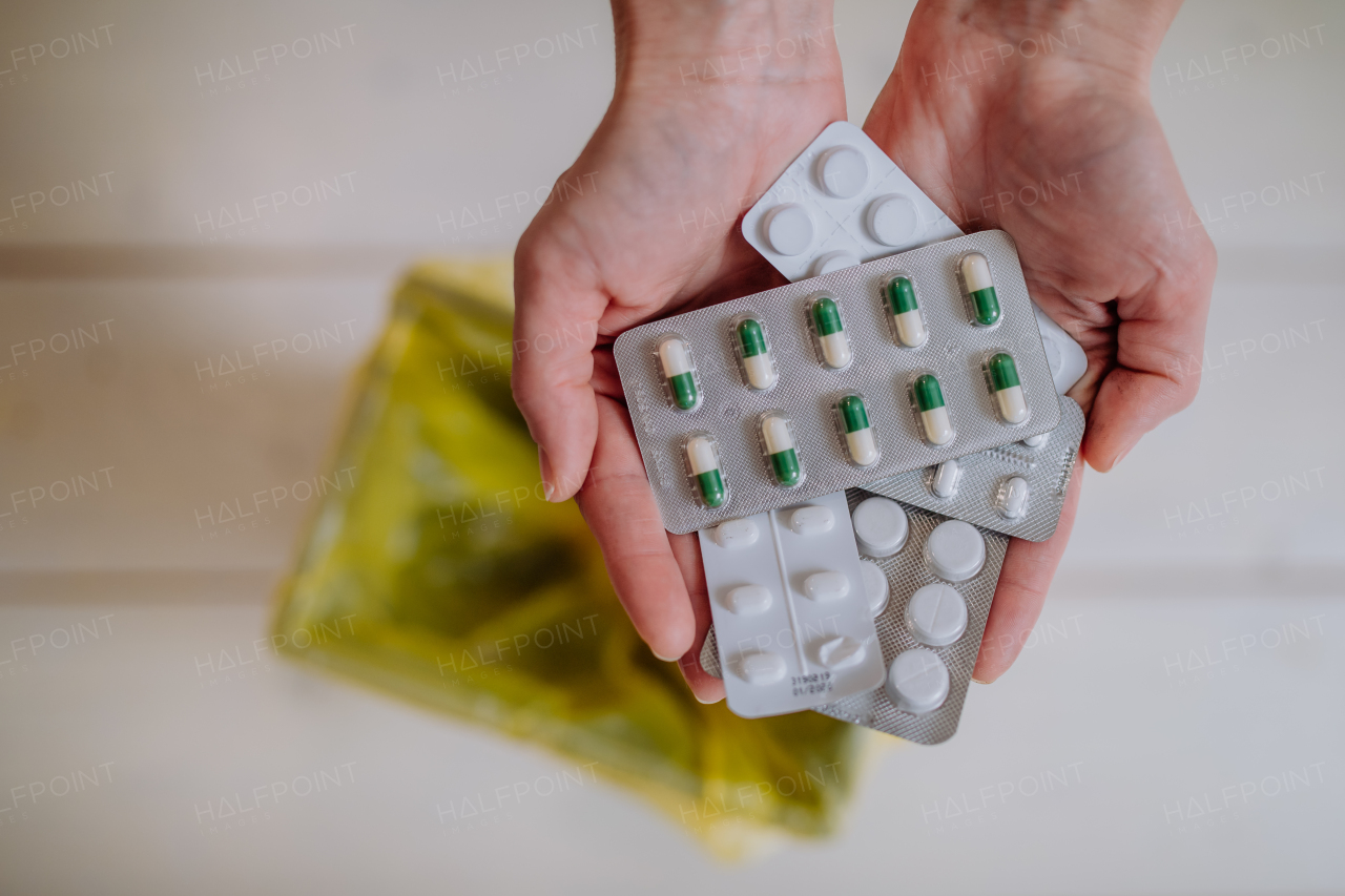 Woman's hands holding and throwing expired pills blisters to the trash bin.