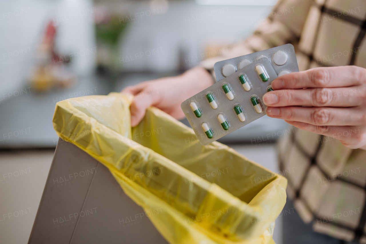 Woman's hands holding and throwing expired pills blisters to the trash bin.