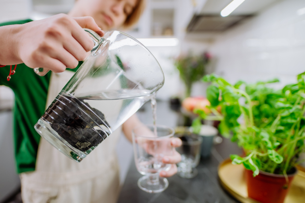 A girl pouring water from jar with shungite stones