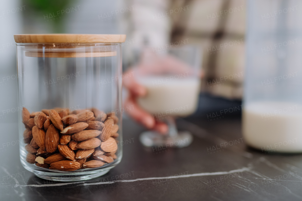 Almonds and almond milk and a glass on kitchen counter. Healthy vegan product concept.