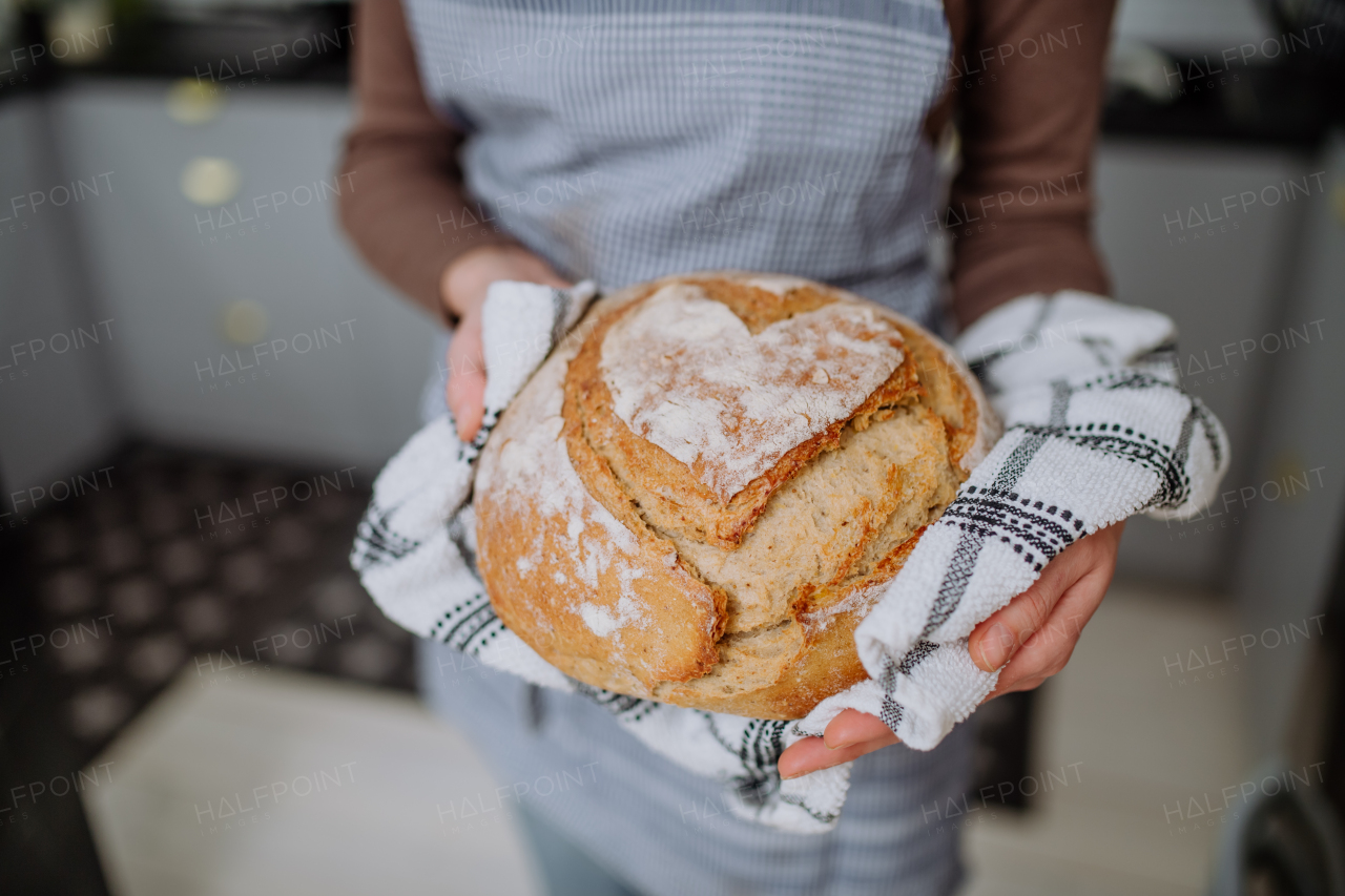 A close-up of woman holding homemade sourdough bread, cooking at home concept.