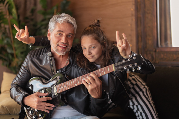 A father rock guitarist having fun and and dancing with his teenage daughter at home.