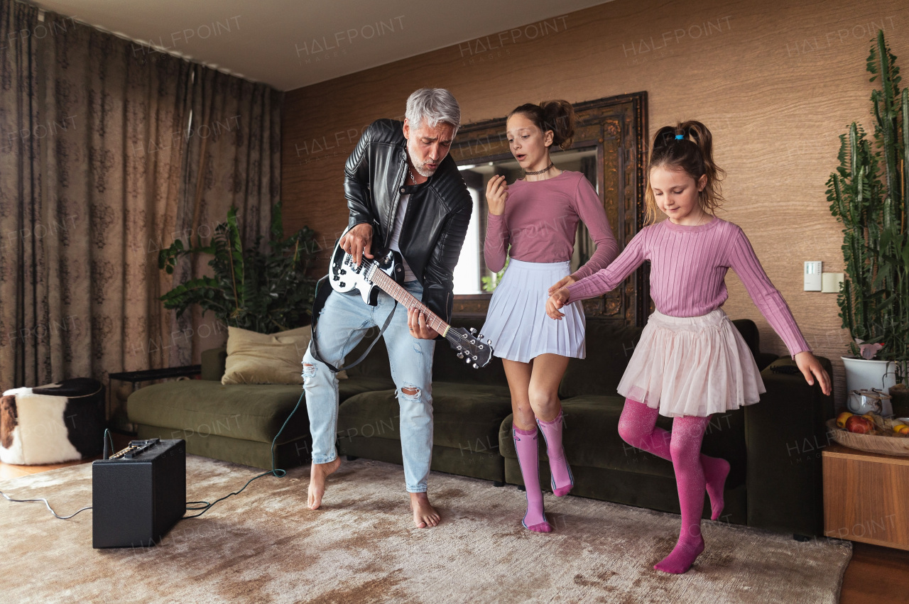 A father rock guitarist having fun and and dancing with his teenage daughter at home.