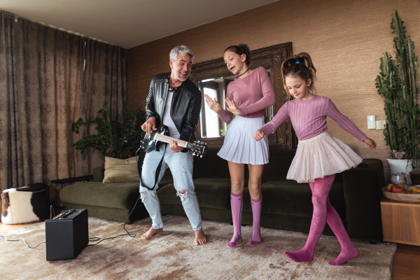 A father rock guitarist having fun and and dancing with his teenage daughter at home.