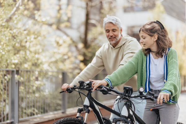 A happy father with teenage daughter on cycle ride in town.