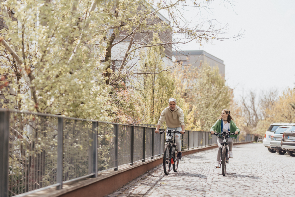 A happy father with teenage daughter on cycle ride in town.