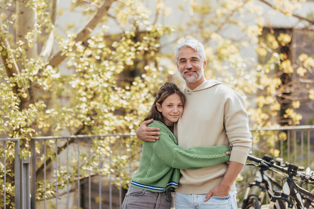 A teenage daughter hugging her father outside in town when spenidng time together.