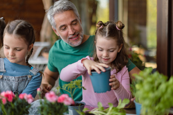 Little daughters helping a father to plant flowers, home gardening concept