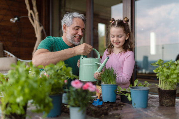 A little daughter helping father to plant flowers, home gardening concept