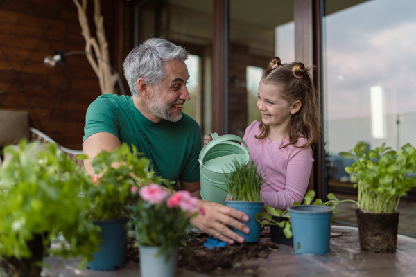 A little daughter helping father to plant flowers, home gardening concept