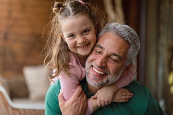 A portrait of little cute daughter hugging her happy father at home.