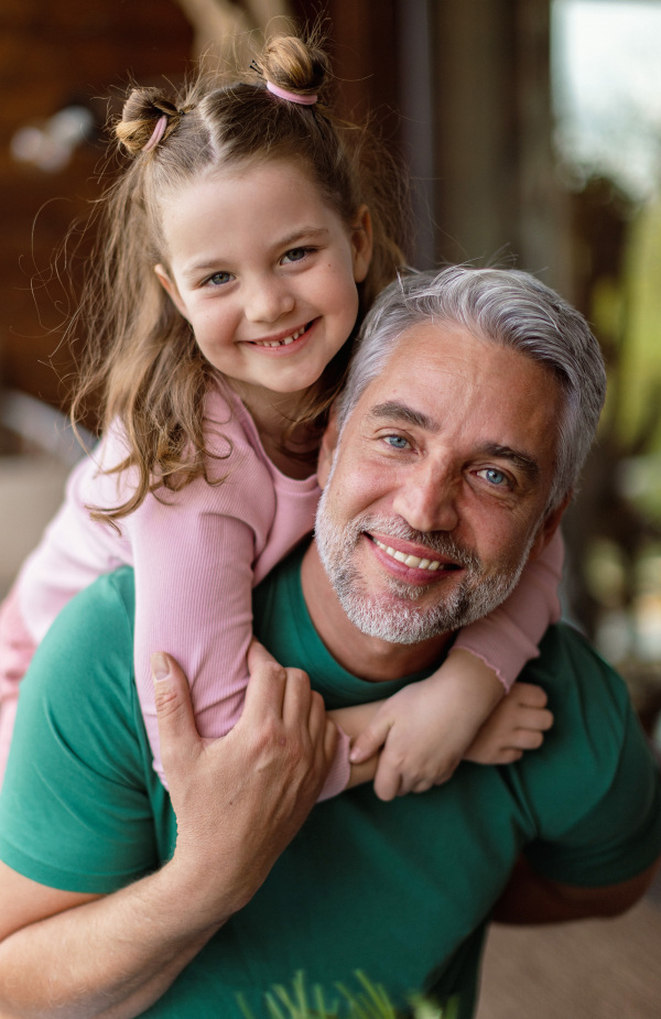 A portrait of little cute daughter hugging her happy father at home.