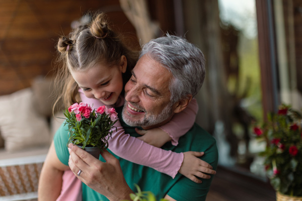 A portrait of little cute daughter hugging her happy father at home.