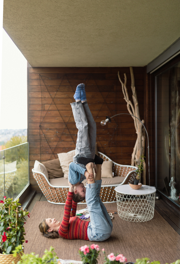 Two little sisters doing acrobatic exercise together at home on a balcony.