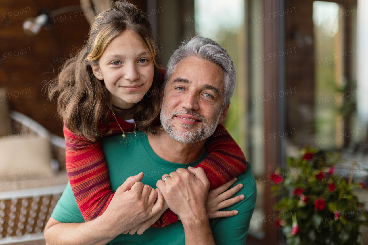 A portrait of teenage daughter hugging her happy father at home.