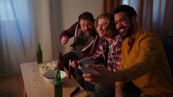 Happy Austrian football fans friends watching football at home and taking a selfie