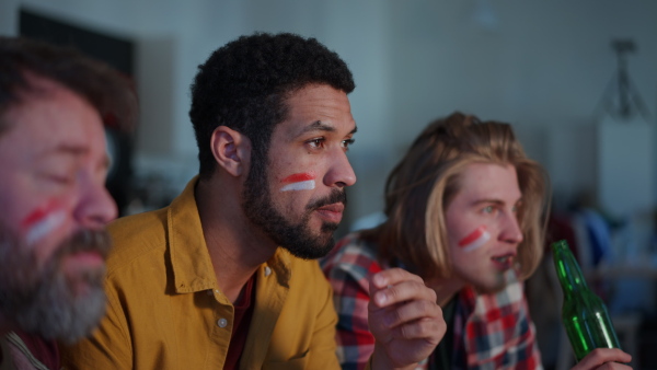 Nervous football fans friends watching live soccer match on TV at home