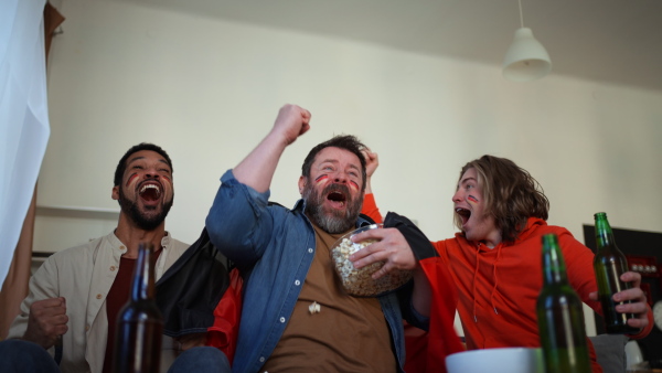 Happy German football fans friends watching a football at home and applauding