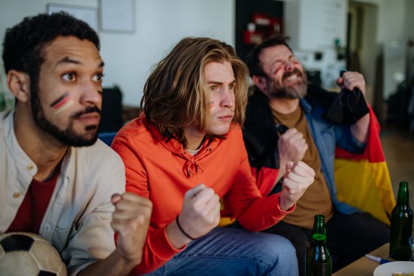 Nervous football fans friends watching a German national team in live soccer match on TV at home