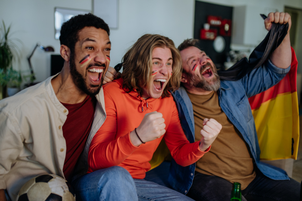 Happy German football fans friends watching a football at home and celebrating.