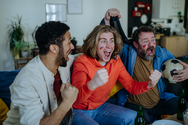 Happy German football fans friends watching football at home and celebrating success