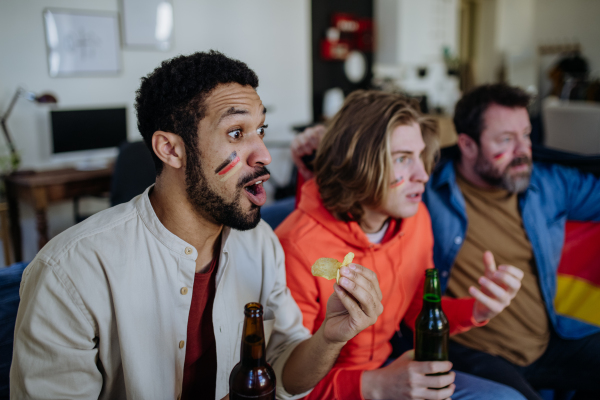 Happy German football fans friends watching football at home and celebrating success