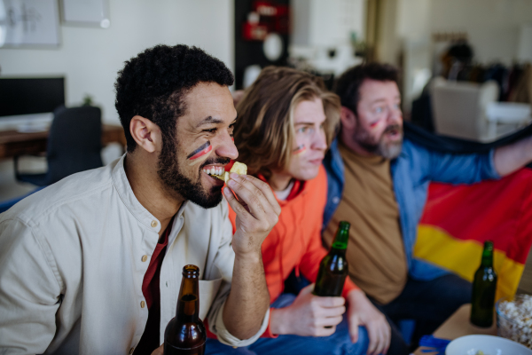 Nervous football fans friends watching a German national team in live soccer match on TV at home