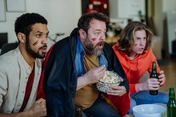 Nervous football fans friends watching a German national team in live soccer match on TV at home