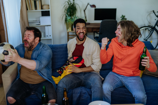 Happy German football fans friends watching a football at home and celebrating.