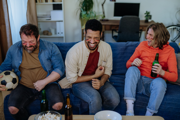 Happy German football fans friends watching football at home and eating the popcorn.