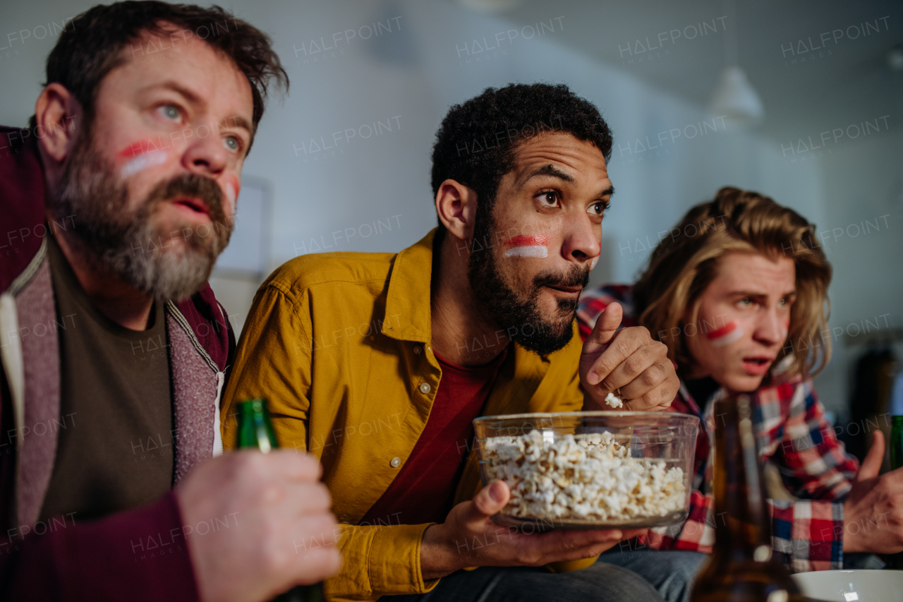 Nervous football fans friends watching a German national team in live soccer match on TV at home