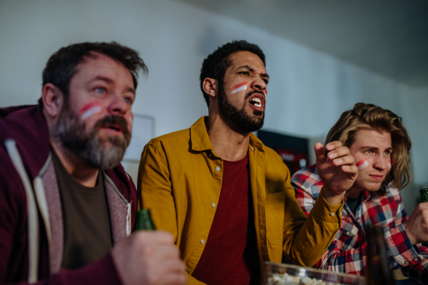 Nervous football fans friends watching a German national team in live soccer match on TV at home