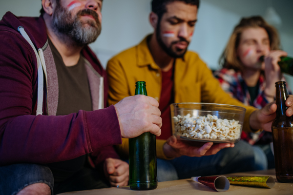 Close-up of football fans friends watching match and eating popcorn.